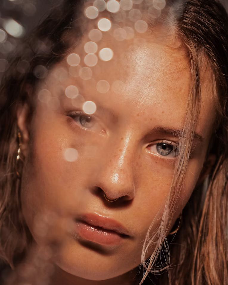 Close-up of a freckled face in warm light with soft out-of-focus highlights