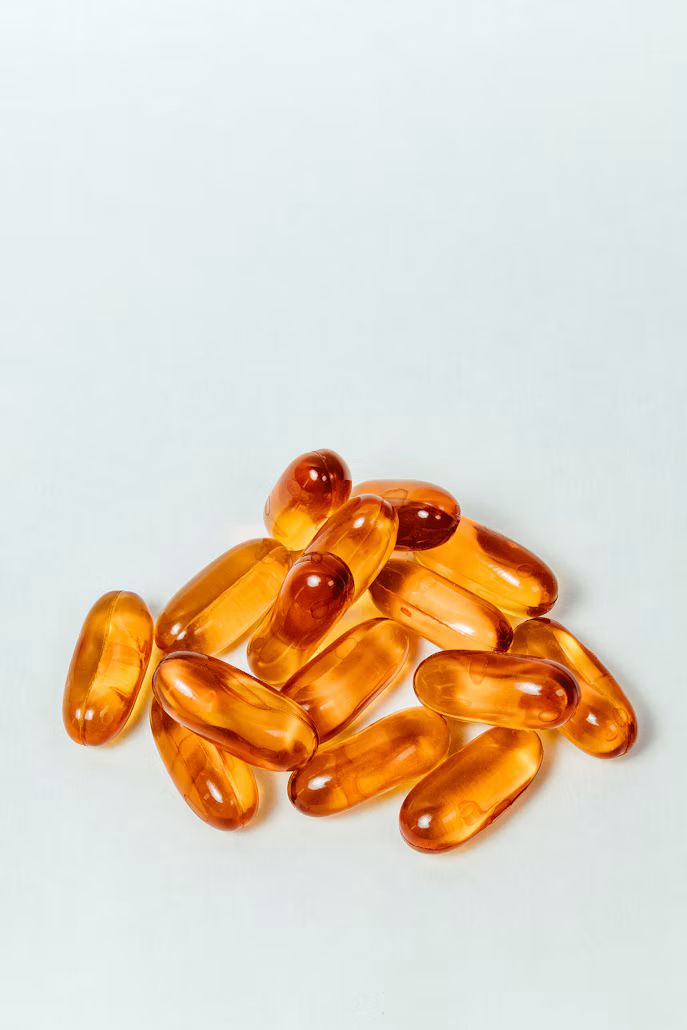 Amber softgel capsules piled on a white surface